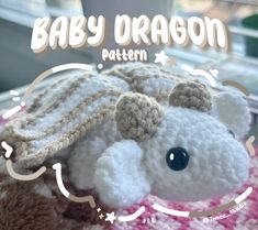 a crocheted stuffed animal laying on top of a blanket with the words baby dragon written above it