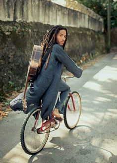 a man with dreadlocks riding a bike down the street