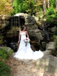 a bride standing in front of a waterfall