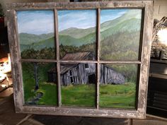 an old window has been painted to look like a barn in the mountains and trees