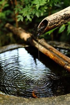 a wooden stick sticking out of the top of a small pond with water running down it