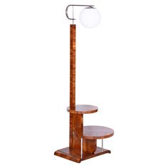 a tall wooden table with a lamp on it's top and two shelves below