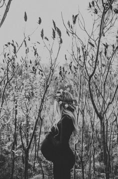 a woman standing in the woods with her back to the camera and looking at trees