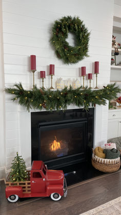 a red truck is parked in front of a fireplace with christmas wreaths on it