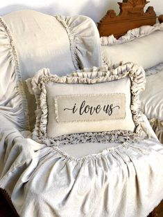 a pillow that says i love us on it sitting on a bed with ruffled pillows