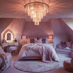 a bedroom decorated in pink and white with a chandelier hanging from the ceiling