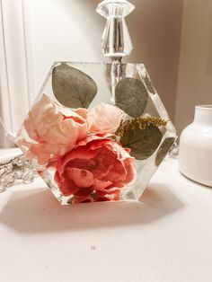 a glass vase filled with flowers sitting on top of a table next to a mirror