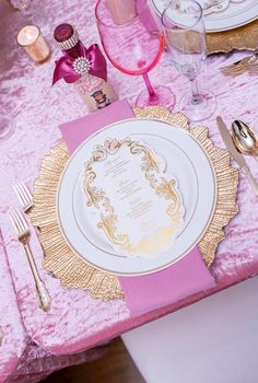 the table is set with pink and gold place settings