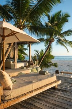 a bed sitting on top of a wooden deck next to the ocean and palm trees