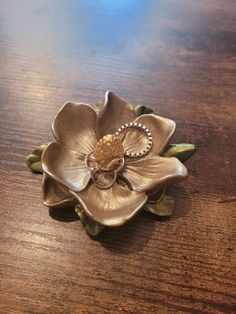 a flower shaped brooch sitting on top of a wooden table