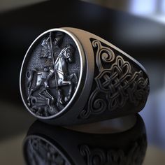 Celebrate the legend of St. George of Lydda with this captivating Dragon Silver Ring. Expertly handcrafted by skilled artisans, this exceptional piece captures the valiant saint slaying the fearsome dragon, inspired by the Christian legend of St. George of Lydda. Made from high-quality sterling silver, this adjustable, unisex ring is designed to last, ensuring its breathtaking appearance endures over time. Perfect for the faithful, history buffs, or anyone who appreciates the inspiring tales of Handmade Viking Ring As A Gift, Handmade Viking Style Ring As Gift, Handmade Viking Style Ring For Gift, Medieval Style Handmade Rings For Gifts, Medieval Style Handmade Rings As Gifts, Handmade Viking Style Ring Jewelry, Handmade Medieval Style Rings Ideal For Gifts, Handmade Medieval Style Rings For Gifts, Handmade Medieval Style Rings As Gift