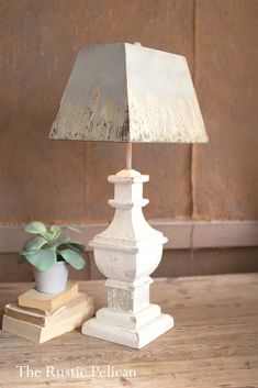 a white lamp sitting on top of a wooden table next to a potted plant