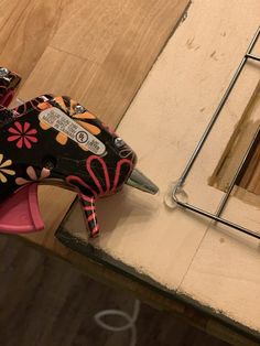 a pair of high heeled shoes sitting on top of a wooden floor next to a mirror