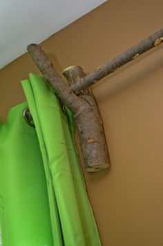 a tree branch hanging on the side of a wall next to a green curtain rod