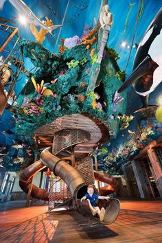 a boy is sitting on a slide in the middle of a room with many decorations