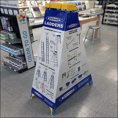 a sign in the middle of a store with ladders on it's sides