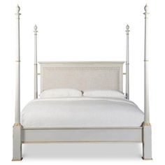 a white bed with four posts and pillows on top of the headboard, in front of a white background