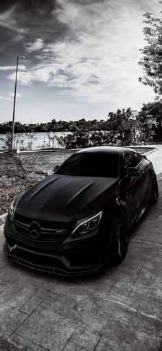 a black car parked in front of a lake