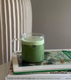 a cup of green liquid sitting on top of some books