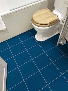 a bathroom with blue tiles and a wooden toilet seat in the middle of the floor