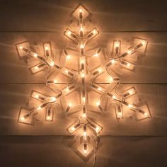 a lighted snowflake is hanging on the wall with lights attached to it's sides