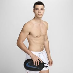 a shirtless man holding a black frisbee in his right hand and wearing white shorts