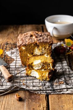 a loaf of cake sitting on top of a cooling rack next to a cup of coffee