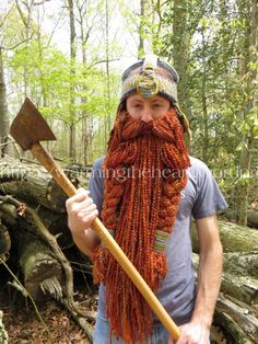 a man with a long beard holding a wooden stick in the middle of a forest