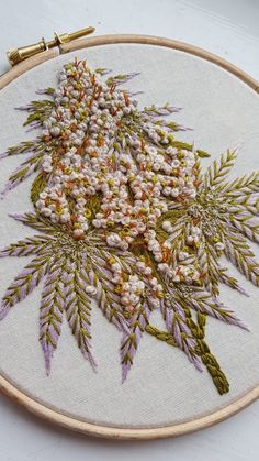 a close up of a embroidery on a hoop with flowers and leaves in the center