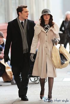 a man and woman are walking down the street holding hands while dressed in winter clothes