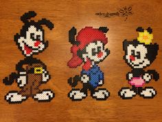 three pixelated mickey and minnie mouses on a wooden table