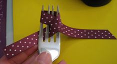 a person holding a fork with a purple polka dot ribbon on it, next to a yellow table