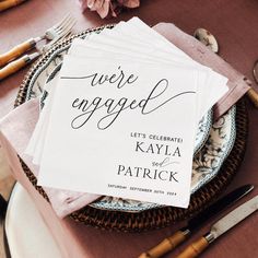 two napkins that say we're engaged on top of each other next to forks and knives