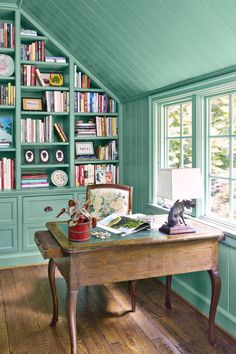 a room with bookshelves and a desk in front of a window filled with lots of books