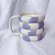 three purple and white checkered mugs stacked on top of each other