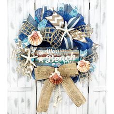 a wreath with seashells and starfish is hanging on a white wooden door