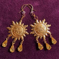 Bring a solar smile to the face of all that look upon your beauty with these dazzling sun drop earrings. These little works of art feature raw stamped brass charms of the smiling sun, and from the smiling sun hangs three vintage pear cut jonquil yellow glass charms. These glass charms have undertones of red, orange, yellow, and green to keep the spectrum of the sun sparkling around you! The earring hook has a clear glass crystal charm and is plated in 22k gold which is perfect for sensitive ears Gold Sun And Moon Festival Jewelry, Gold Sunburst Earrings With Sun Design, Gold Sun And Moon Design Jewelry For Festivals, Gold Jewelry With Sun And Moon Design For Festivals, Spiritual Sun Design Jewelry For Festival, Festival Sun And Moon Dangle Jewelry, Gold Symbolic Earrings With Sun And Moon Design, Bohemian Sunburst Jewelry With Sun Design, Symbolic Gold Earrings With Sun And Moon Design