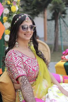 a woman sitting on top of a chair wearing a yellow and pink sari dress