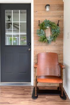 a chair sitting in front of a door with a wreath on the wall behind it