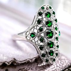 Step into timeless elegance with our Vintage Rhodium Plated 925 Solid Sterling Silver Simulated Emerald Ring. This exquisite piece is expertly crafted, featuring round-cut vibrant green simulated emerald stones that instantly captivate with their radiant hue. The ring is stamped with 925, ensuring its authenticity and superior quality. Each facet of this sterling silver ring is meticulously polished, granting it a luxurious luster that will elevate any ensemble. This striking ring showcases the craftsmanship and attention to detail synonymous with vintage jewelry. The rhodium plating not only enhances its impressive shine but also provides a protective finish, ensuring durability and long-lasting beauty. Ideal for a variety of occasions - from special events to everyday wear - this versati Luxury Faceted Round Cut Jewelry, Luxury Jewelry With Polished Round Stone, Luxury Sterling Silver Emerald Ring With Gemstone Accents, Luxury Sterling Silver Radiant Cut Emerald Ring, Luxury Vintage Rings Stamped 925, Luxury Faceted Green Rings, Luxury Green Faceted Rings, Luxury Radiant Cut Emerald Ring In Sterling Silver, Luxury Radiant Cut Green Ring