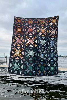 a large quilt hanging from the side of a body of water