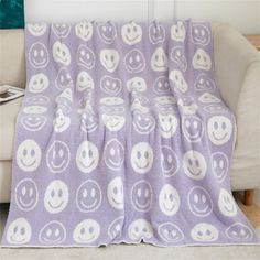 a blanket with smiley faces on it is sitting on a chair in front of a couch