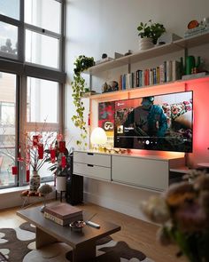 a living room filled with furniture and a flat screen tv mounted on a wall next to a window