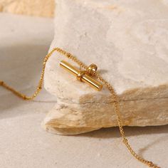 The T Bar Anklet stands out with its sleek, minimalist design in 18k gold plating. This understated piece adds a modern, elegant touch to any look, perfect for those who appreciate subtle yet impactful fashion statements. Anklet Gold, Tarnished Jewelry, Gold Anklet, Beaded Anklets, Gold Piece, Bar Pendant, Royal Jewelry, Chain Anklet, Jewelry Pouch