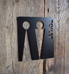 a pair of scissors sitting on top of a piece of black metal next to a wooden wall