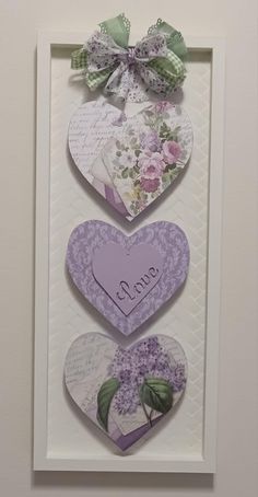 three heart shaped cards with the words i love you written on them, hanging in a white frame