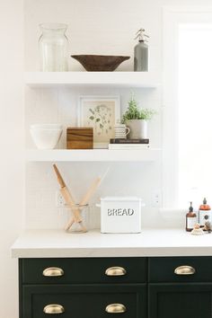 a kitchen with white walls and black cabinets, gold handles on the drawers is filled with various items