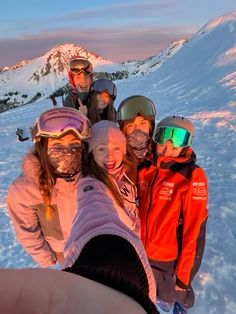 a group of people standing on top of a snow covered slope wearing ski goggles