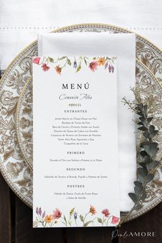 the menu card is placed on top of a plate with greenery and flowers in it