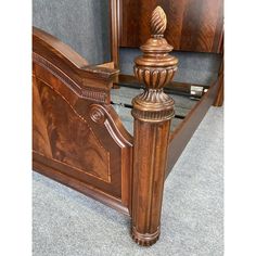 a wooden bed frame with an intricate headboard and foot board on carpeted flooring